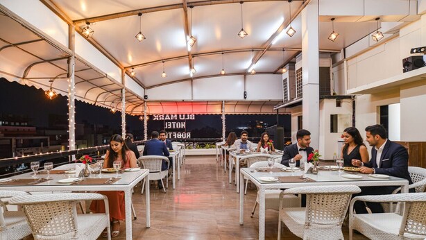 A restaurant with outdoor seating, white wicker chairs, and tables. - Fabhotel Blu Mark (Indore)