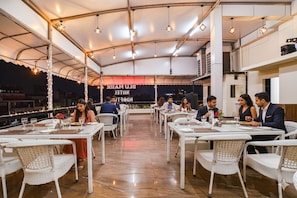 A restaurant with outdoor seating, white wicker chairs, and tables. - Fabhotel Blu Mark (Indore)