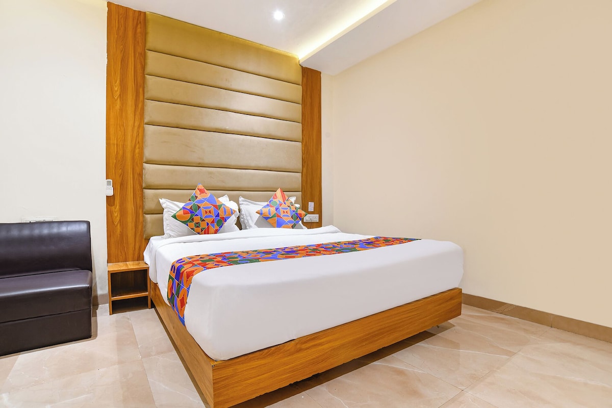 Een moderne hotelkamer met een groot bed, een houten hoofdeinde en een kleurrijk geometrisch plaids.