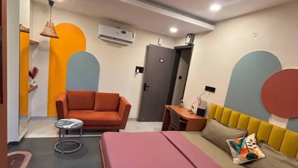 Quarto moderno com cama, sofá, escrivaninha e ventoinha de teto.