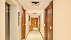 Un couloir d’hôtel avec des portes en bois, un comptoir d’accueil et un sol dégagé.