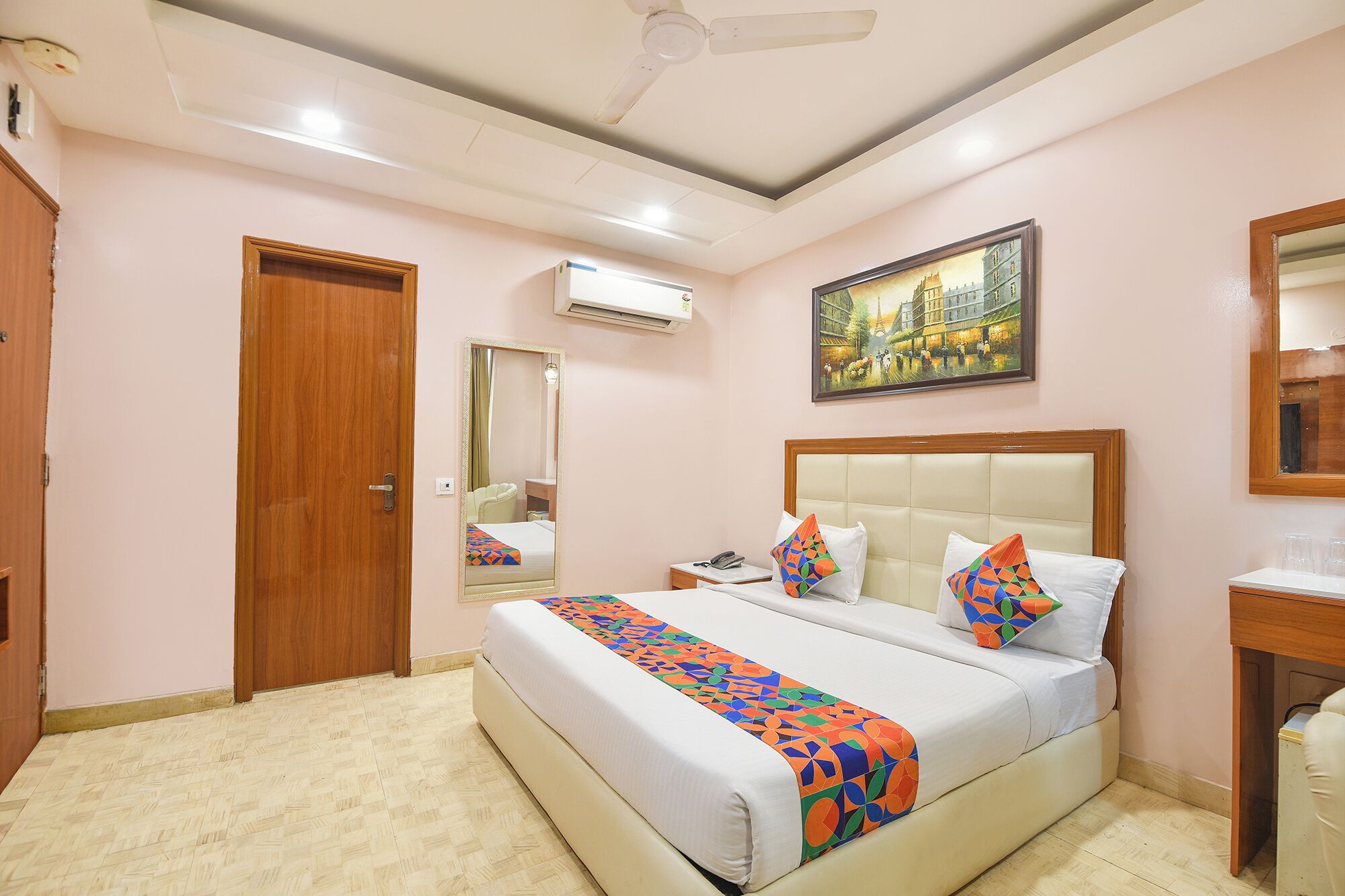 Habitación de hotel con una cama grande, una mesita de noche, un espejo y un cuadro en la pared.
