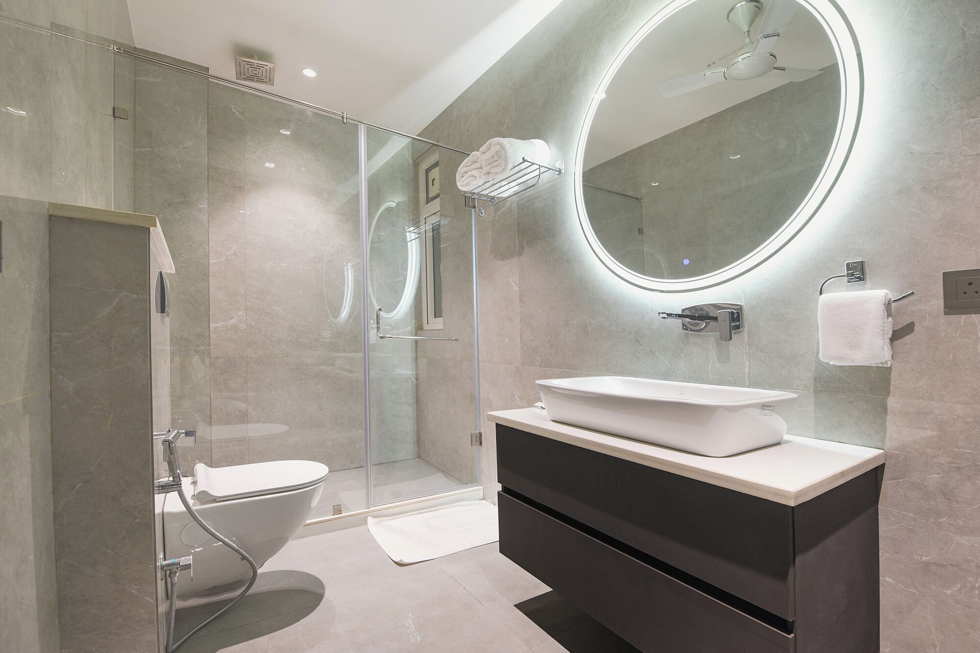 A modern bathroom with a glass-enclosed shower, a vanity with a sink, and a large mirror.