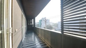 A narrow corridor with a checkered floor, leading to a balcony with horizontal blinds. - FabHotel Ivory Leaf- Nr Artemis Hospital Gurgaon (Gurugram)