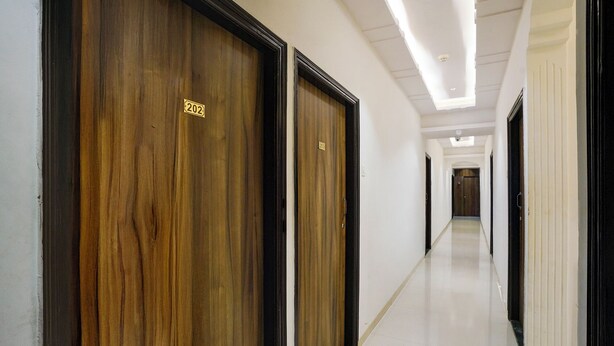 A corridor with wooden doors marked with numbers 202 and 203, leading to a room. - Via Blissful Stays (Navi Mumbai)