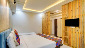 A bedroom with a bed, a TV mounted on the wall, and wooden paneling. - Via Blissful Stays (Navi Mumbai)