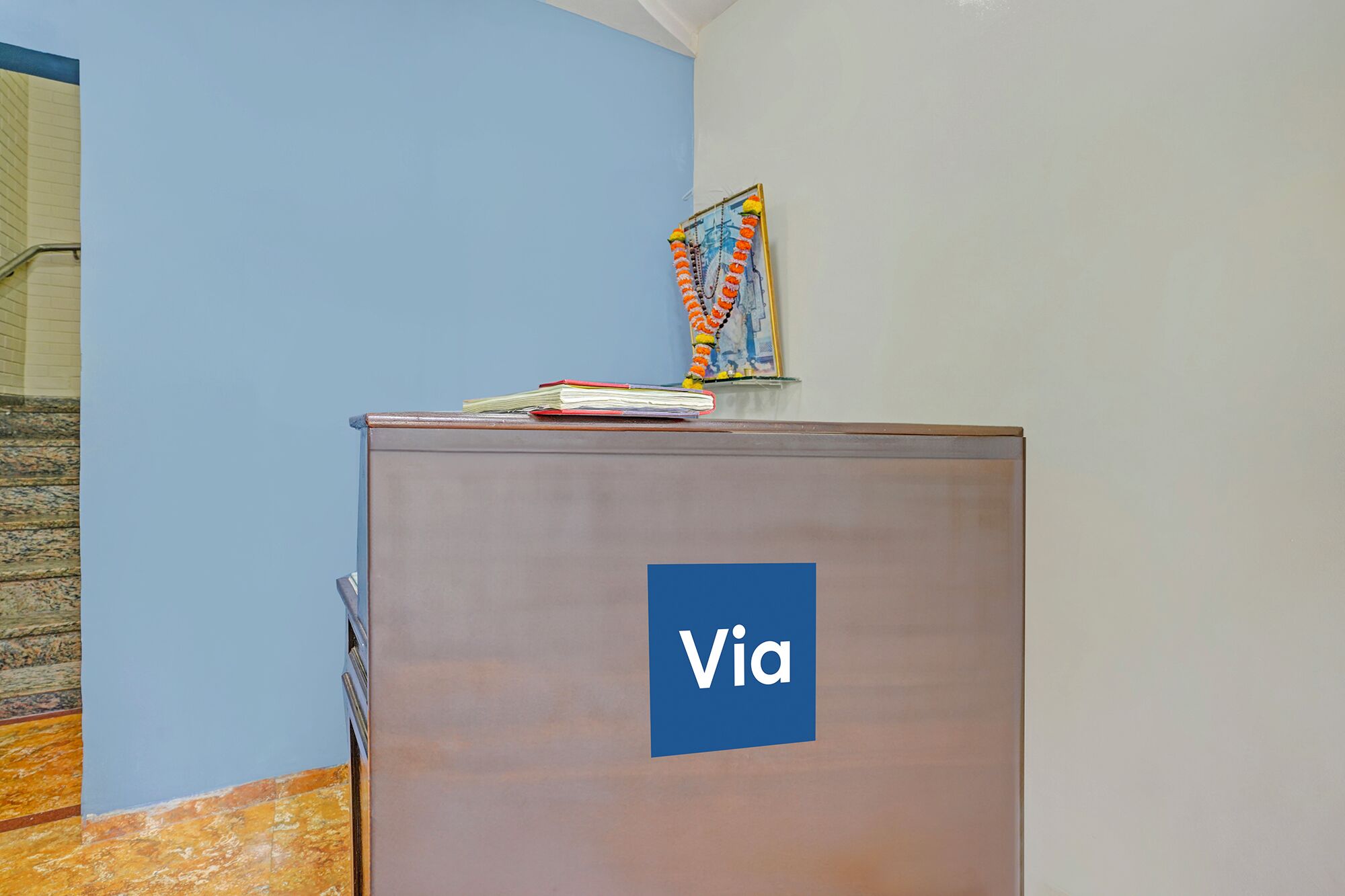 Una recepción con un cartel de 'Via', una obra de arte enmarcada y una escalera al fondo.