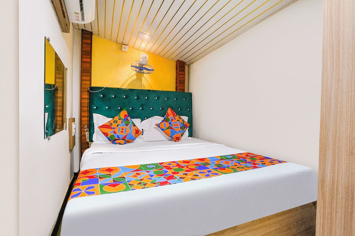 Un letto con una coperta dai colori vivaci e motivi geometrici, una testiera imbottita e due cuscini decorativi.