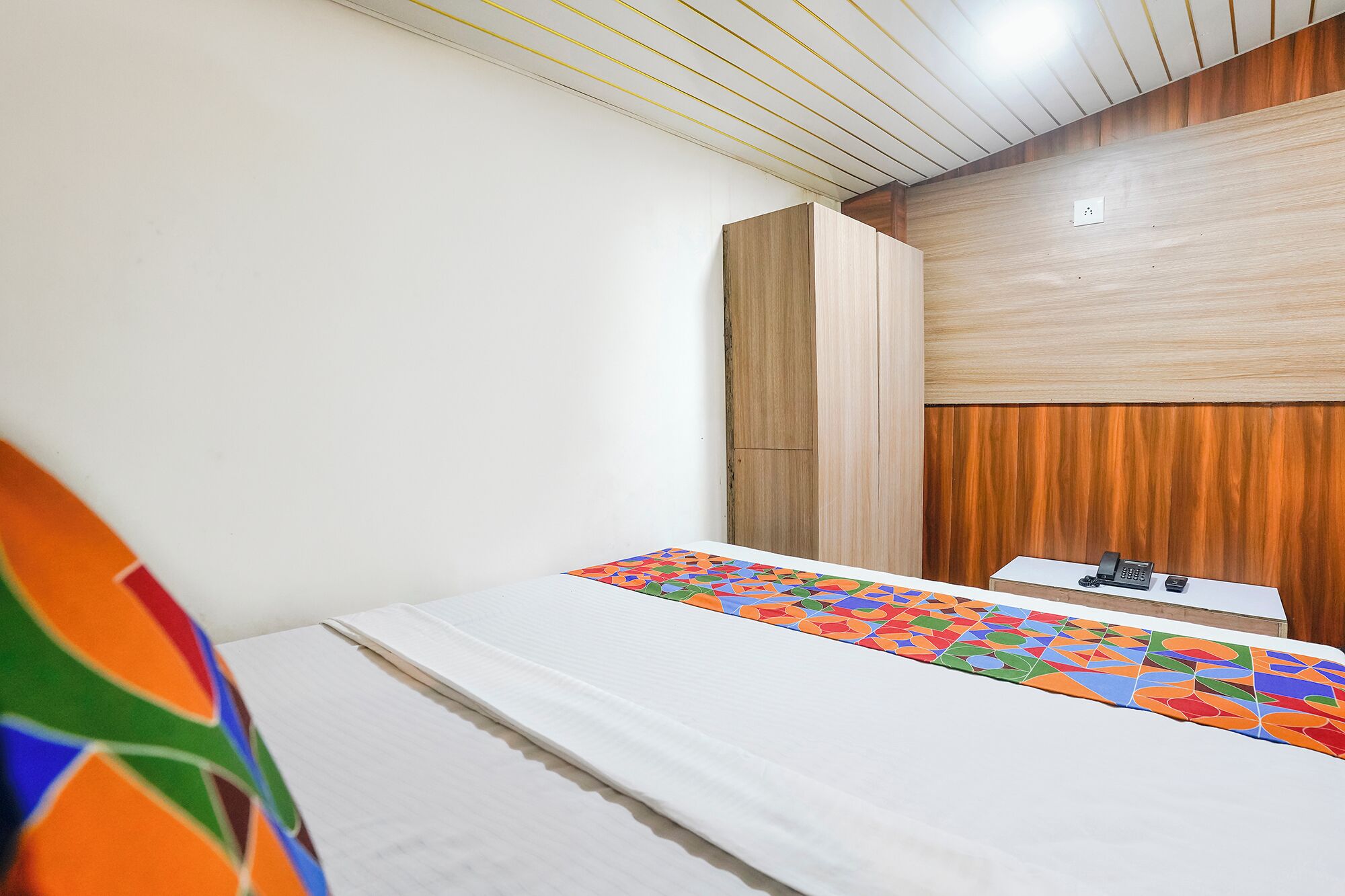 Une chambre d’hôtel avec un lit, un bureau avec un téléphone et un mur recouvert de panneaux en bois.