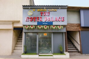 A hotel entrance with a sign reading 'The Hotel Palace' and a logo above it.