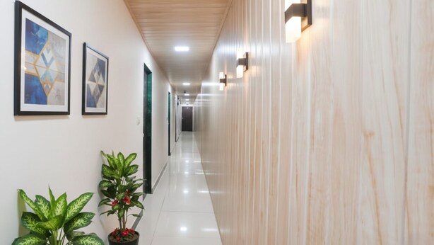 A hallway with framed artwork on the walls, potted plants, and a wooden ceiling. - Via The Palace (Mumbai)