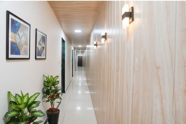 Un corridoio con quadri appesi alle pareti, piante in vaso e soffitto in legno.