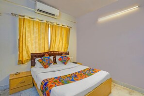 Un dormitorio con cama, mesita de noche, aire acondicionado y lámpara de pared.