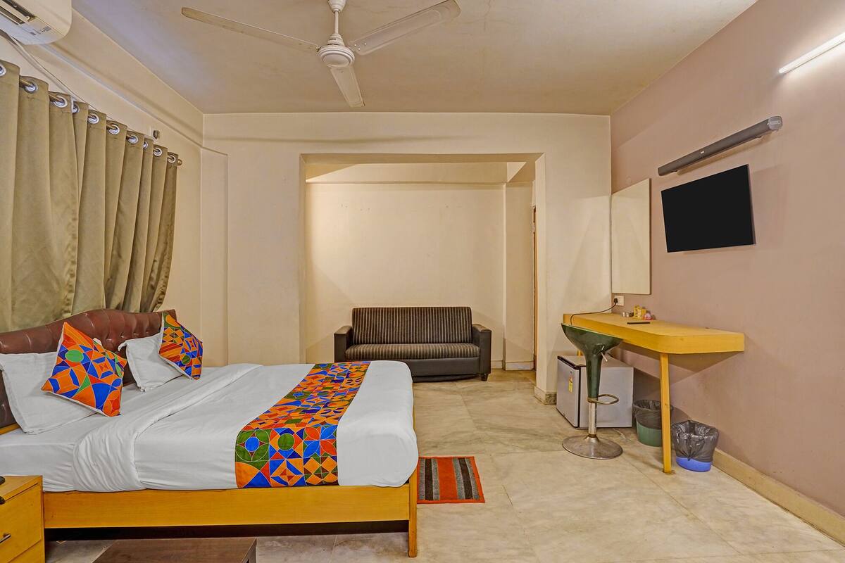 Ein Hotelzimmer mit einem Bett, einer Couch, einem kleinen Tisch, einem Spiegel und einem Deckenventilator.