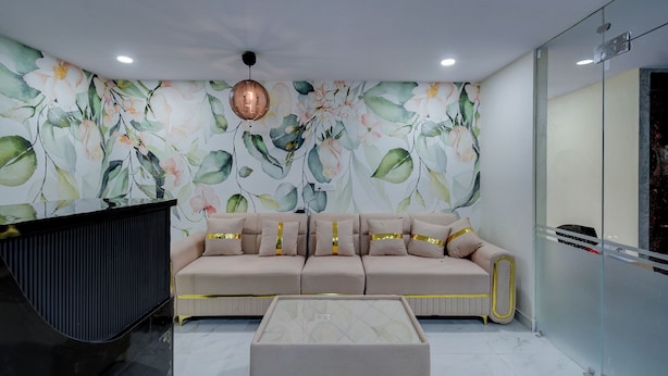 Een moderne woonkamer met een beige bank, een glazen scheidingswand en bloemenbehang.
