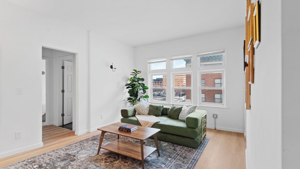 A modern living room with a green sofa, a wooden coffee table, and a patterned rug. - Close To Downtown | Luxury Getaway Apartment In Midtown (Detroit)