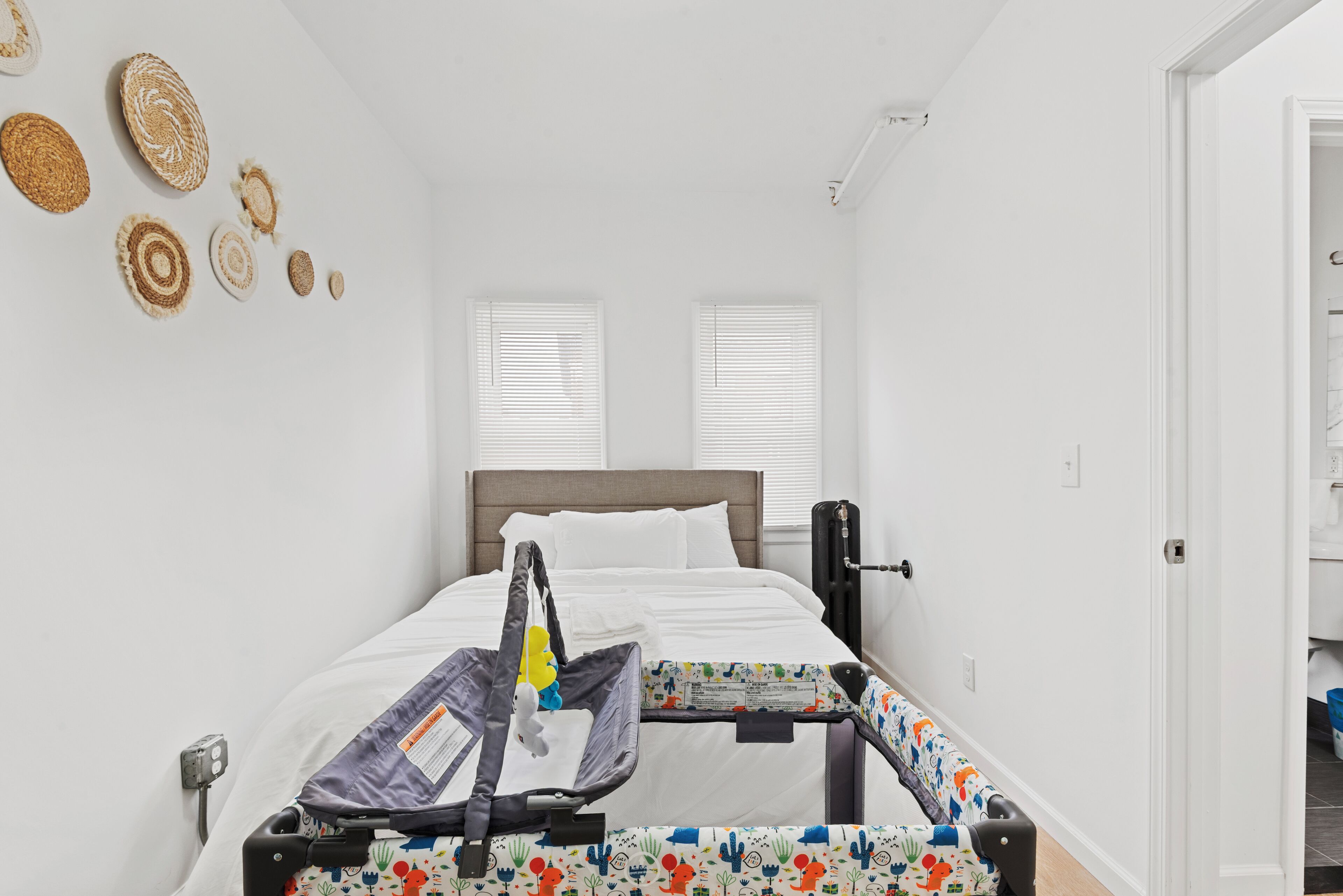 Un dormitorio con una cama, una cuna y un calentador de pared.