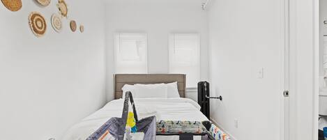 Un dormitorio con una cama, una cuna y un calentador de pared.