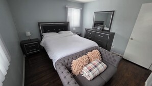 Een slaapkamer met een bed, nachtkastjes, een kaptafel, een spiegel en een deur.