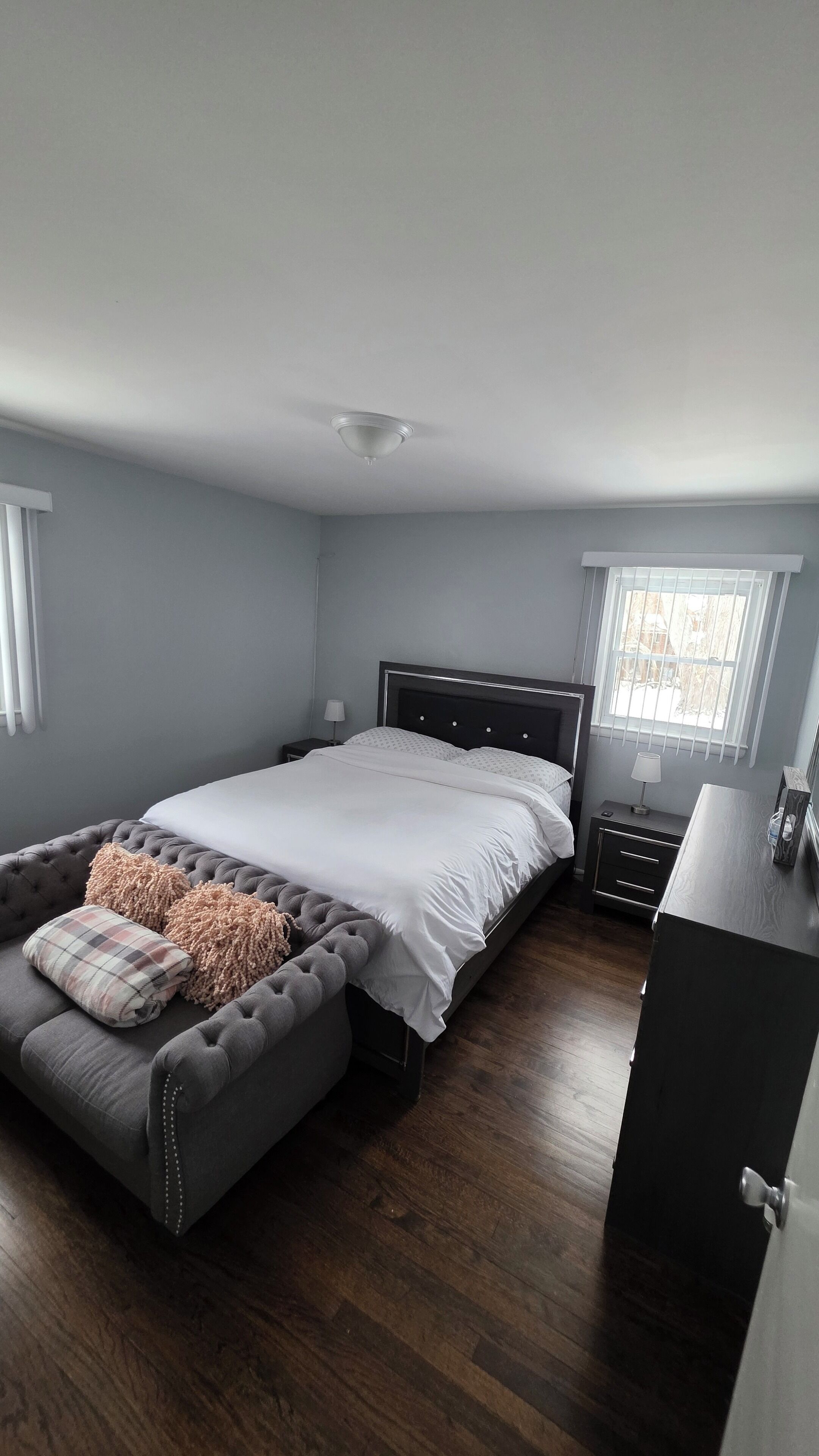 A bedroom with a bed, a nightstand, a dresser, and a window.