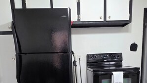 Een kleine keuken met een zwarte koelkast, een fornuis en een magnetron.
