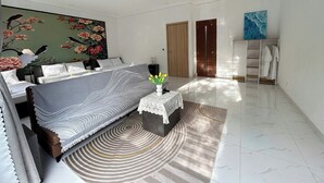 Une chambre à coucher moderne avec un grand lit, une petite table ornée de fleurs, une armoire et un tableau accroché au mur.