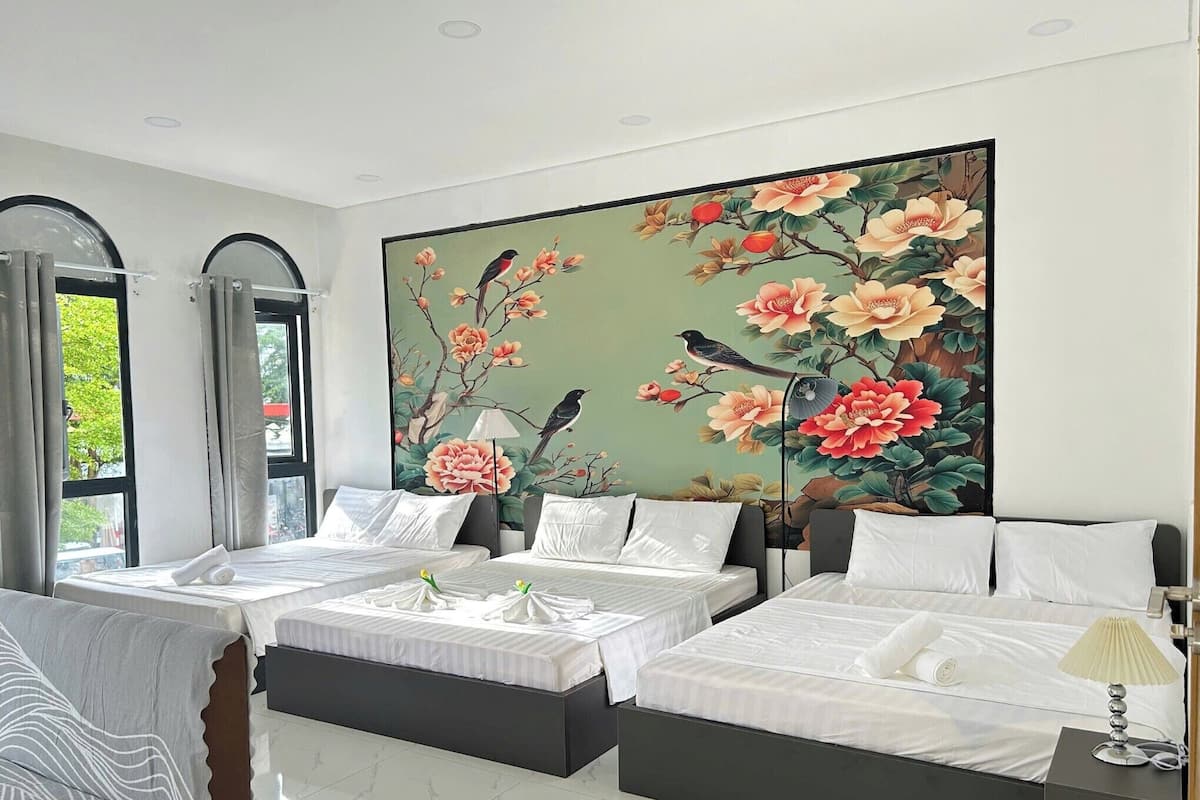 Een hotelkamer met twee bedden, een groot bloemenmural en uitzicht door het raam.