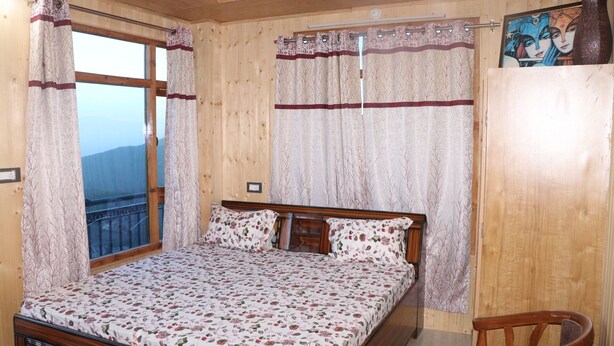 Une chambre à coucher avec un lit en bois, une literie à motifs floraux et une vue par la fenêtre.