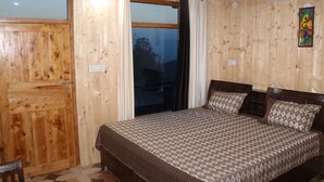 Une pièce aux murs lambrés, avec un lit, une fenêtre ornée de rideaux et un tableau accroché au mur.