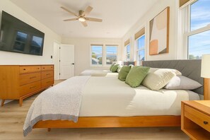 Une chambre avec un grand lit, un ventilateur de plafond, une télévision et une fenêtre donnant sur un beau paysage.