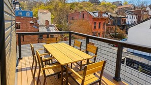 Eine Holzterrasse mit Tisch und Stühlen, mit Blick auf eine Stadt mit historischen Gebäuden.