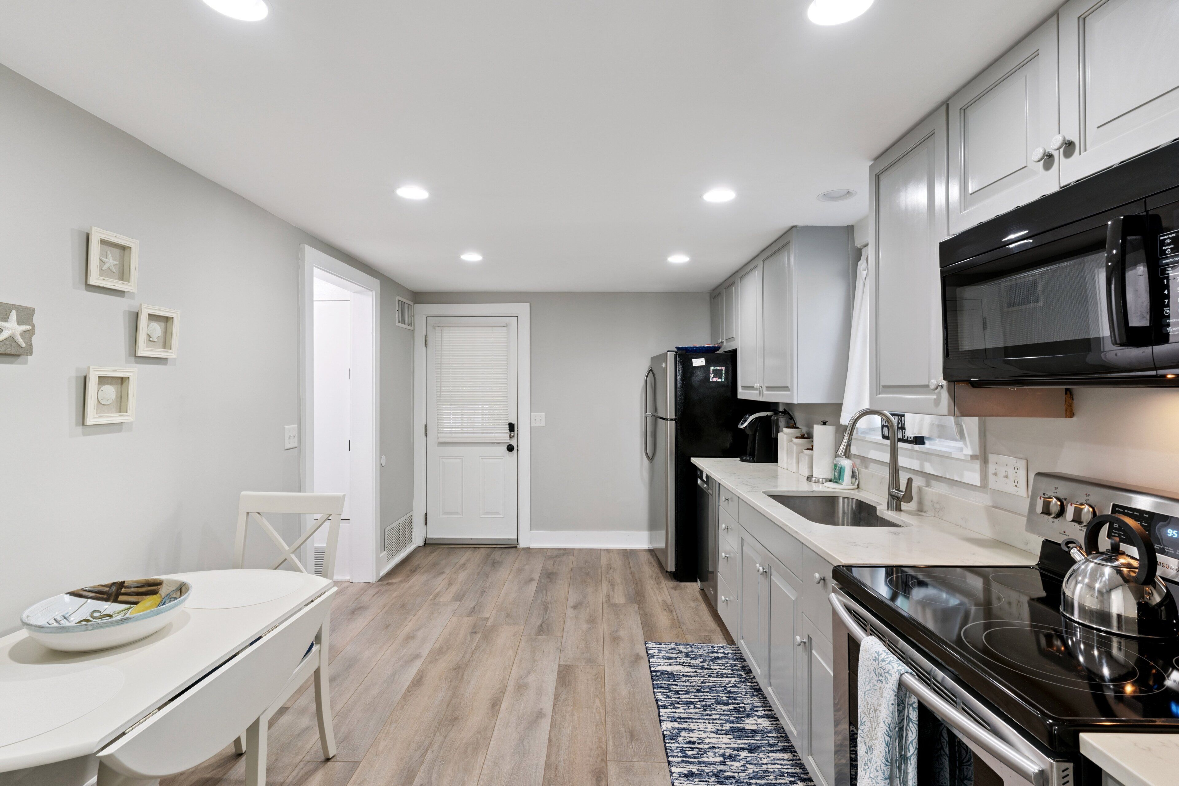 A modern kitchen with white cabinets, a black stove, and a stainless steel refrigerator.