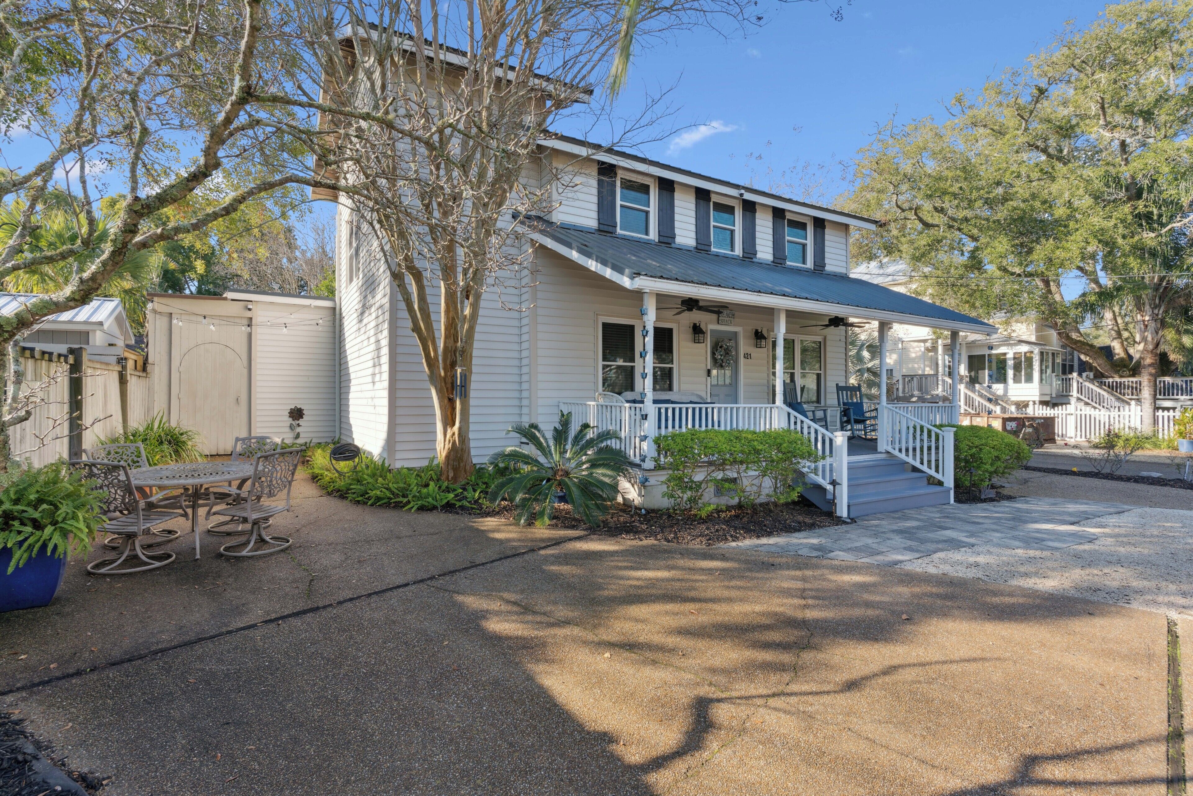 A two-story house with a porch, a covered front porch area, and a small outdoor seating area with a table and chairs.