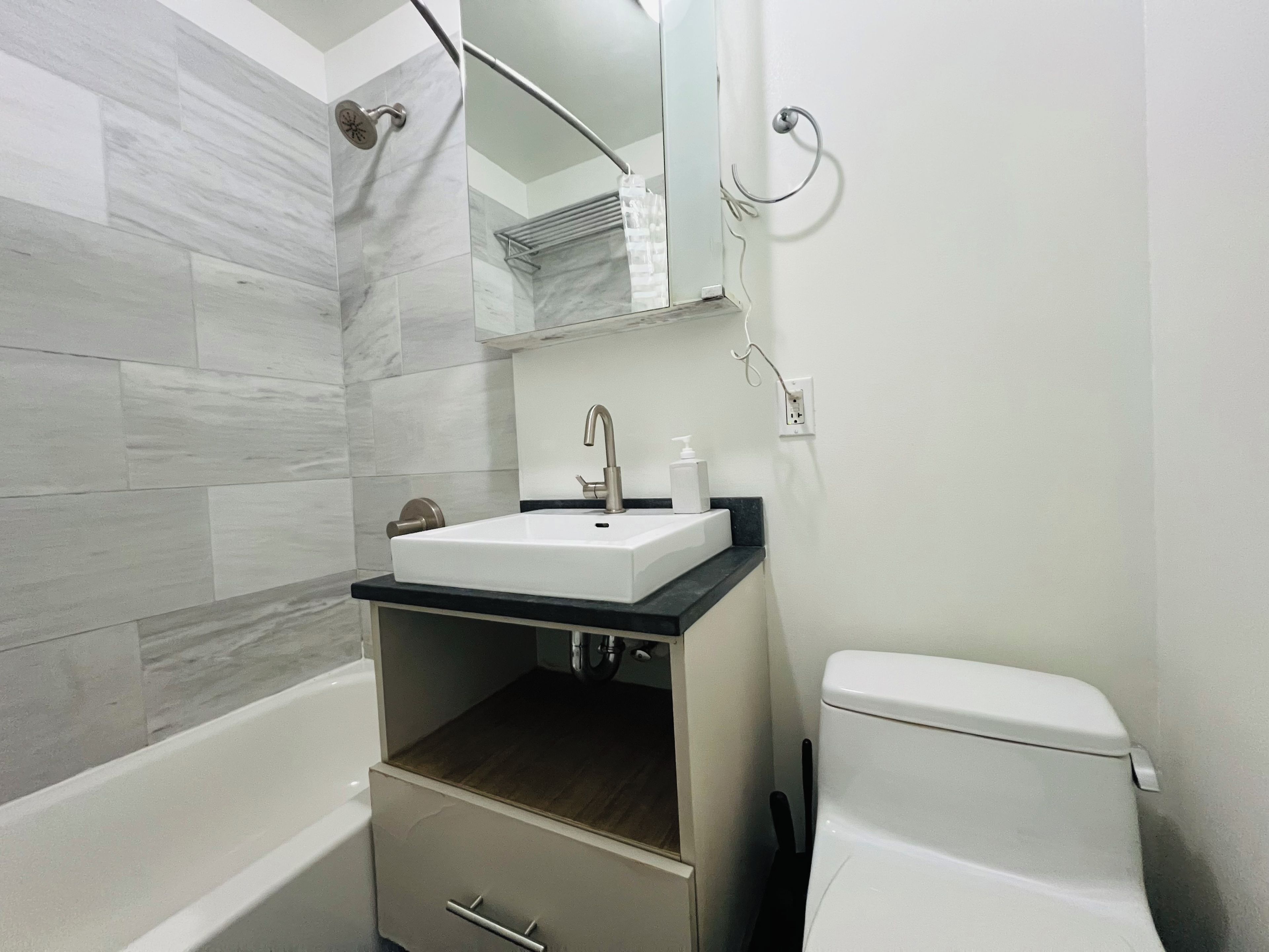 A bathroom with a bathtub, a sink with a mirror above it, and a toilet.