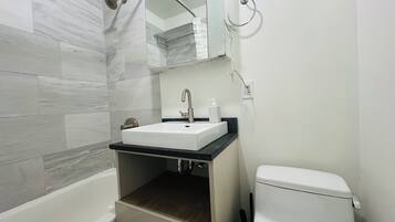 A bathroom with a bathtub, a sink with a mirror above it, and a toilet.