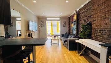 A modern living space with a kitchen area, a dining table, and a seating area with a sofa and armchairs.