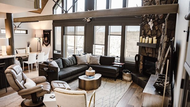 Una sala de estar moderna con un sofá seccional, una chimenea y ventanas grandes.