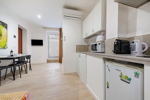 Una cocina moderna con microondas, cafetera y refrigerador. Hay una zona de comedor con sillas y una mesa.