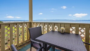 Een balkon met rieten meubilair en uitzicht op zee.