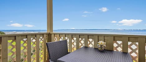 A balcony with wicker furniture and a view of the ocean.
