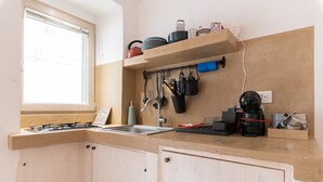 Une cuisine avec une fenêtre, une cuisinière, un évier et un plan de travail sur lequel sont disposés divers ustensiles de cuisine.