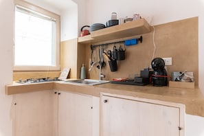 Eine Küche mit Fenster, einem Herd, einer Spüle und einer Arbeitsplatte mit verschiedenen Küchenutensilien.