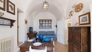 A dining area with a wooden table, chairs, and a blue bowl. There is a blue sofa and a cabinet in the background. - Borgo&Mare Terrace Sant'Oronzo Palace (Ostuni)