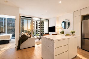 A modern apartment with a kitchen, living area, and a balcony with a city view. - Luxe 1BR + Study Balcony Pool Gym Sauna Steam. Prime CBD Location (Victoria)