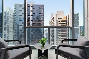 A modern room with two chairs, a small table, and a view of high-rise buildings. - Luxe 1BR + Study Balcony Pool Gym Sauna Steam. Prime CBD Location (Victoria)