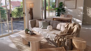 Un salon chaleureux avec un canapé, une table basse et une table à manger. Une grande fenêtre offre une vue sur la verdure environnante.