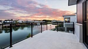 Een modern balkon met uitzicht op een rustige rivier en een zonsonderganglucht.
