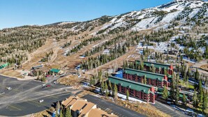 Ein Skigebiet mit Parkplatz, Gebäuden und einem Bergpanorama.