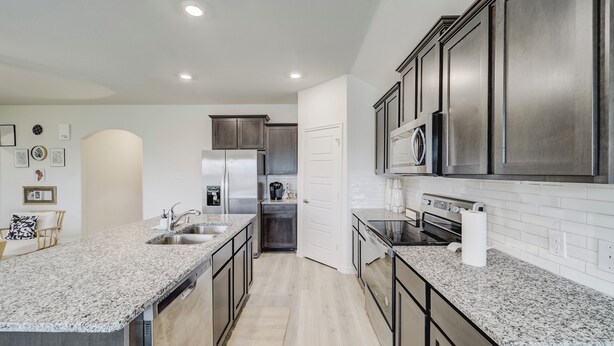 A modern kitchen with granite countertops, stainless steel appliances, and dark cabinetry.