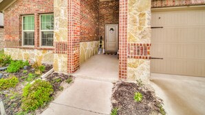 A two-story house with a brick exterior, a stone archway entrance, and a garage.